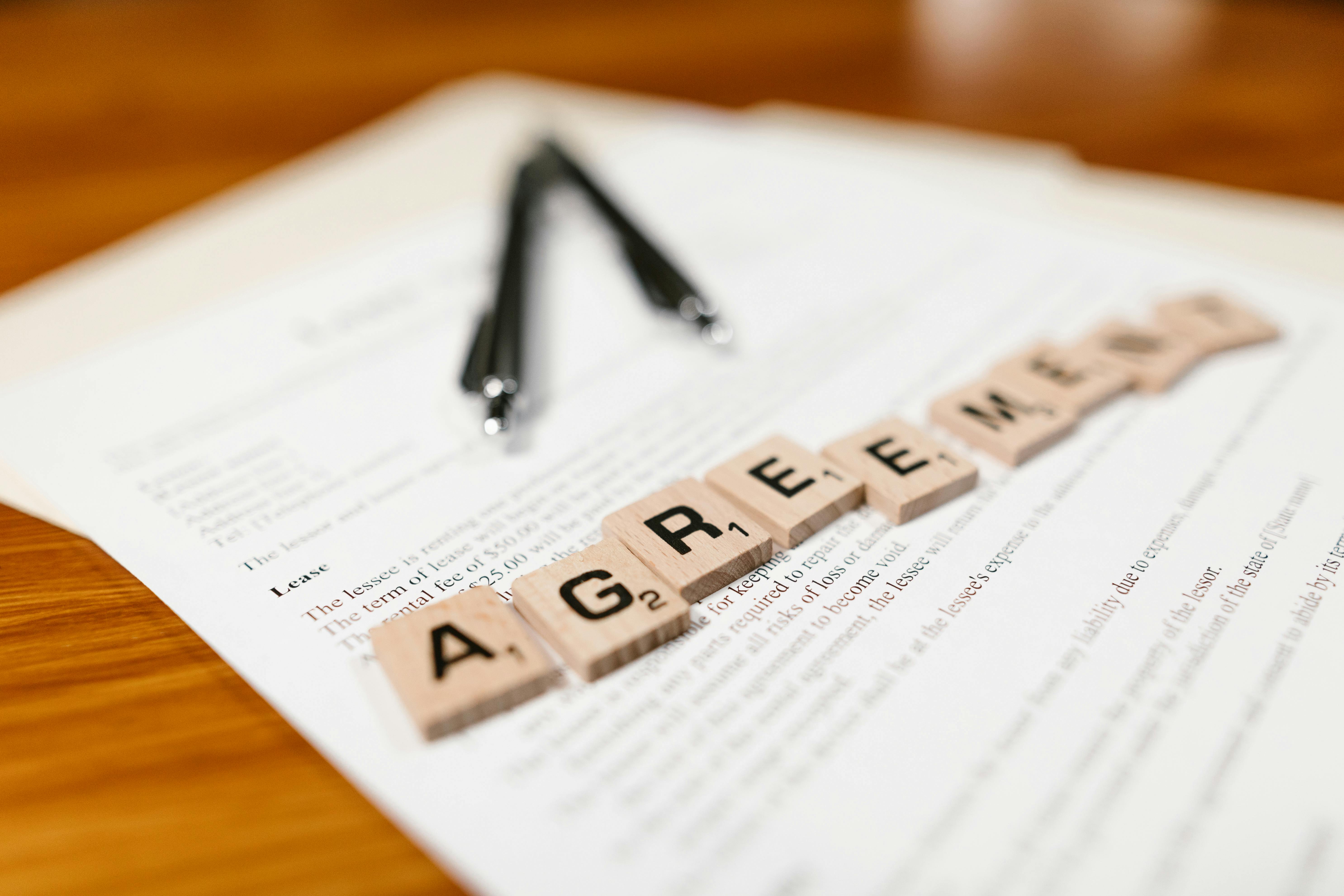 a lease agreement with two pens and scrabble tiles spelling out the word 