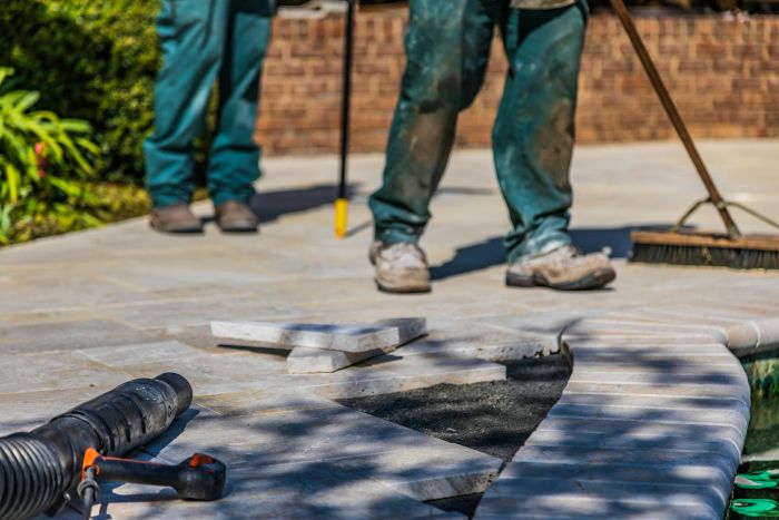 People doing maintenance on a stone walkway